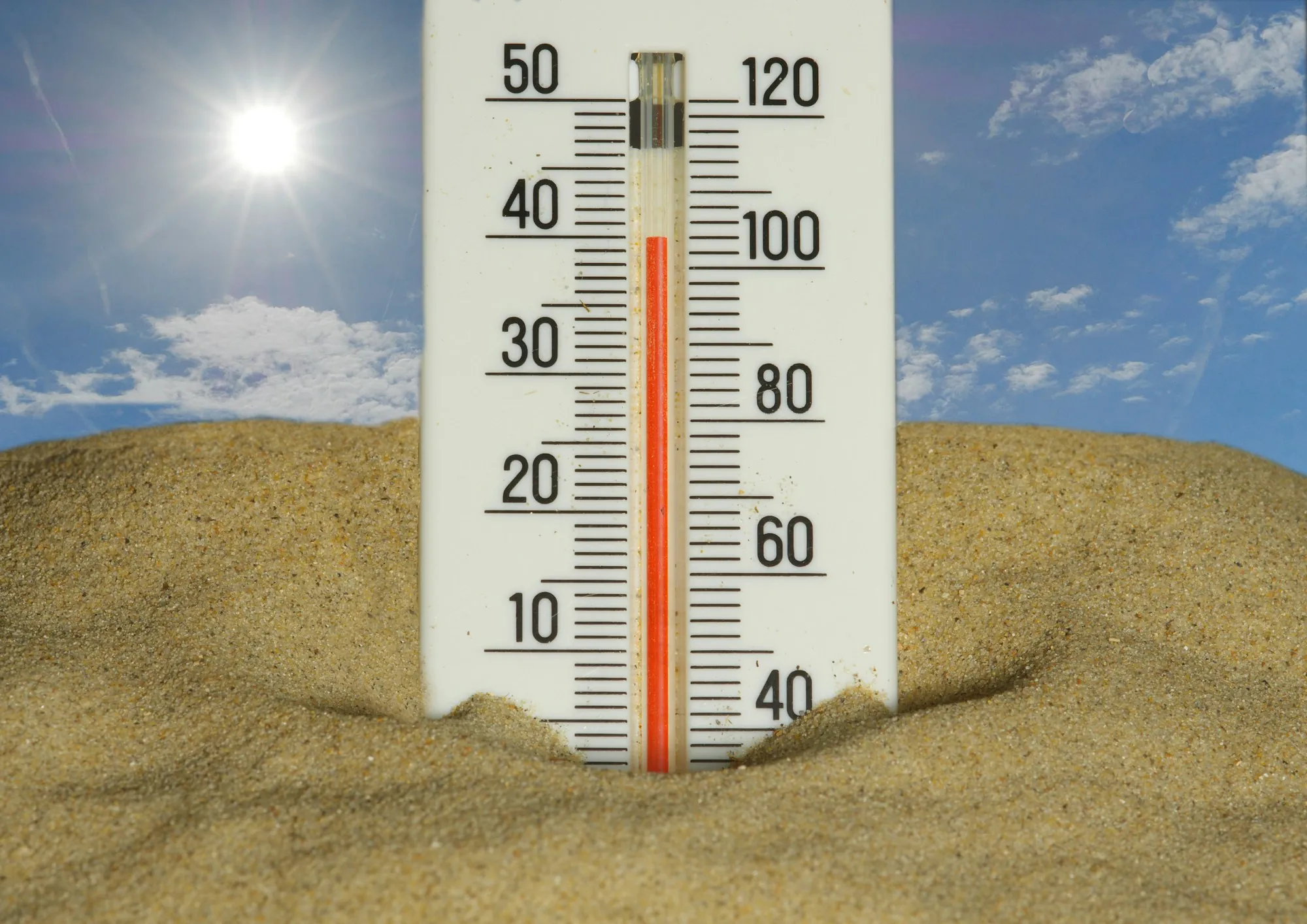 Thermometer in hot sand reading high under the sun